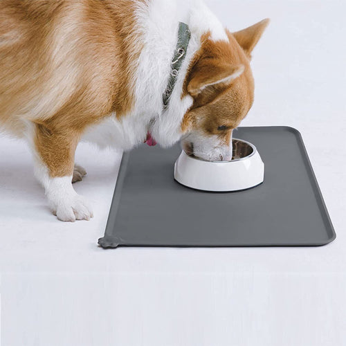 A corgi eating from a white bowl placed on a grey silicone mat