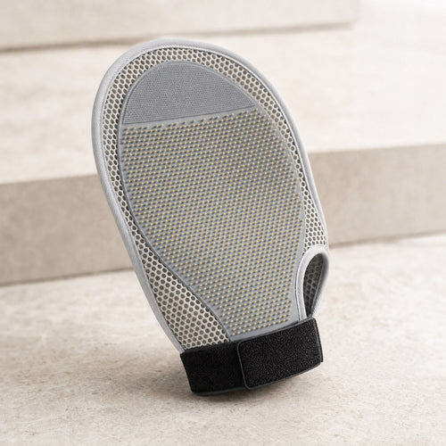 A grey pet grooming mitt with a soft pin bed and black wrist strap