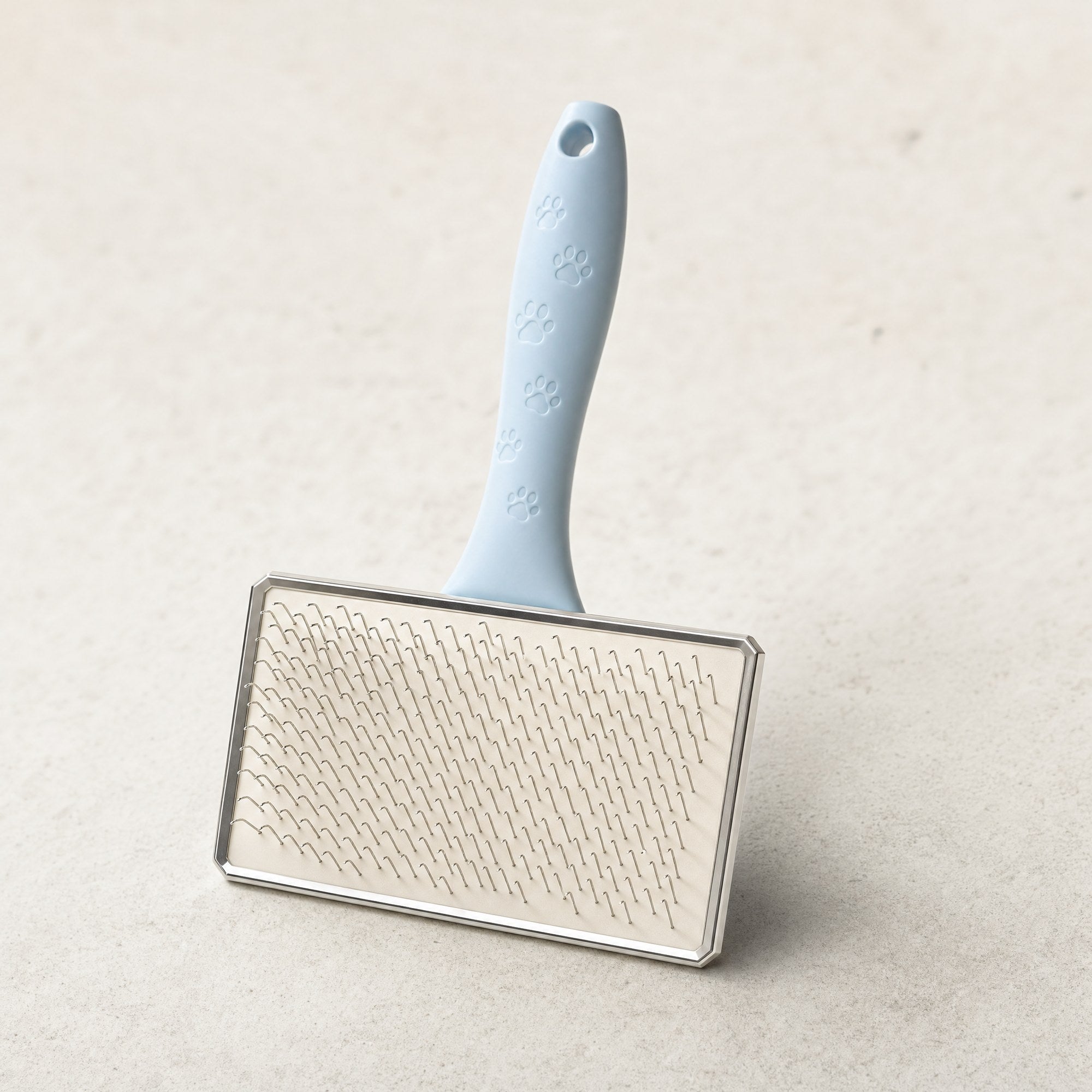 A pet grooming slicker brush with a pale blue handle